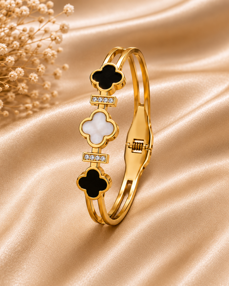 One gold four-leaf shell bangle with black and white clover inlays on champagne satin