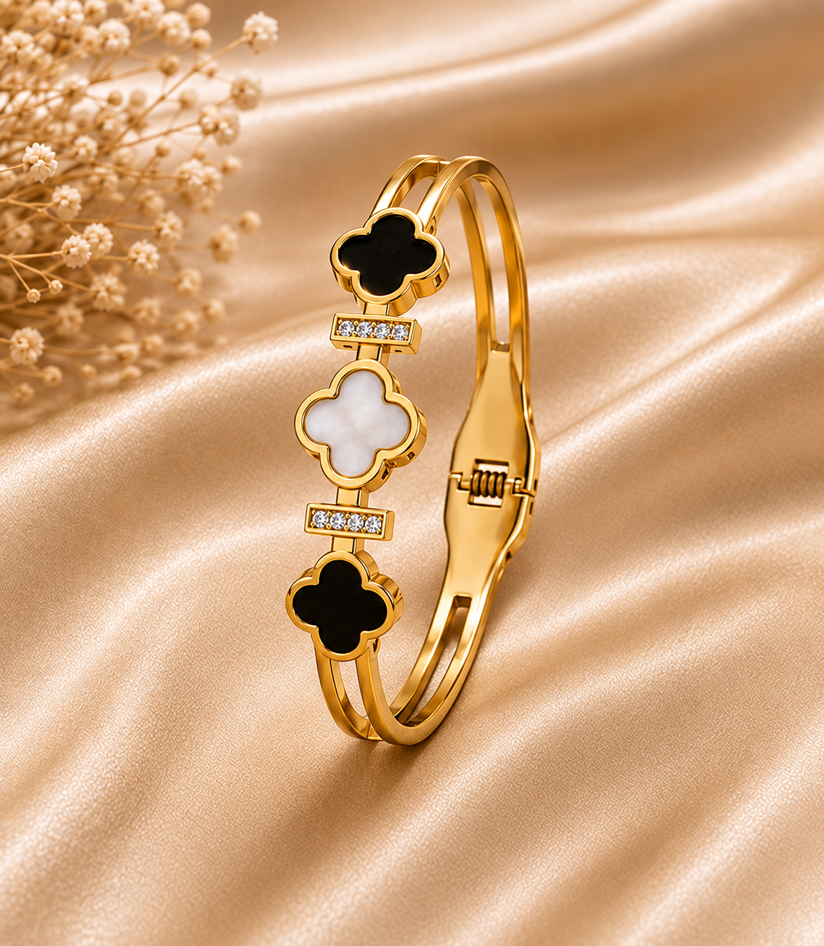 One gold four-leaf shell bangle with black and white clover inlays on champagne satin